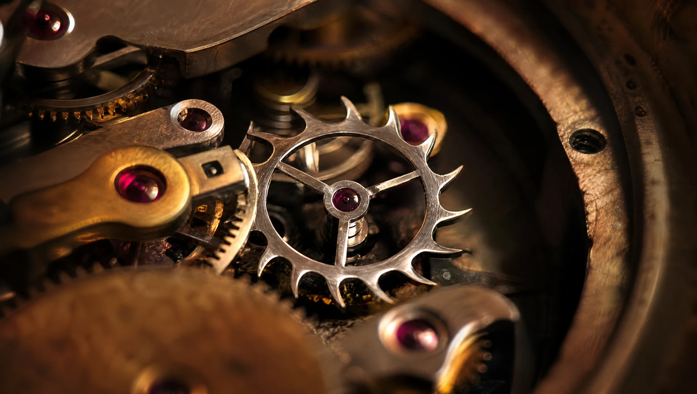 Close-up of a steel escape wheel and jewelled brass parts inside a clock movement